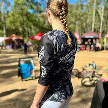 Load image into Gallery viewer, Womens black camo long sleeve Jersey. Made by Shredding Trails. Contours seamlessly around body armour like a glove. Proudly manufactured in Australia from recycled plastic bottles.
